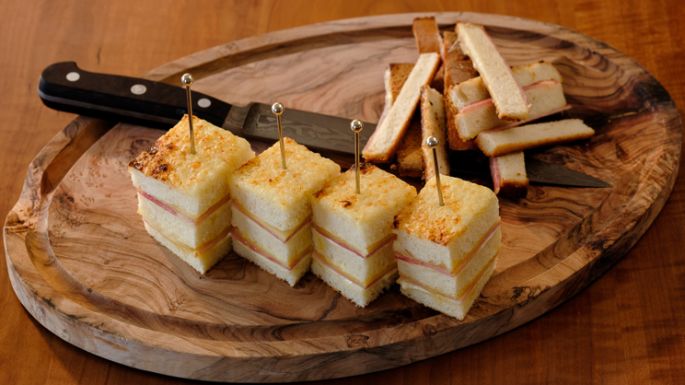 Rezeptidee, Gericht mit Käse Croque Monsieur, angerichtet auf einem Holzbrett