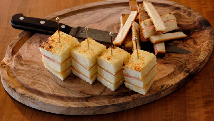 Gericht mit Käse Croque Monsieur, angerichtet auf einem Holzbrett