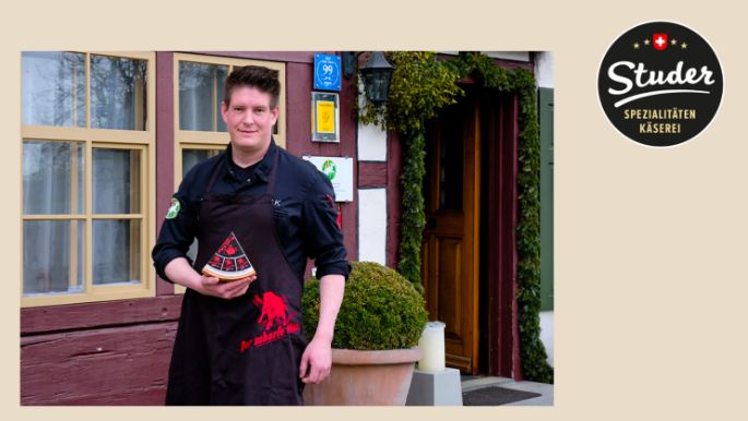 Schweizer Sternekoch Christian Kuchler, der ein Stück «Der scharfe Maxx» in der Hand hält.