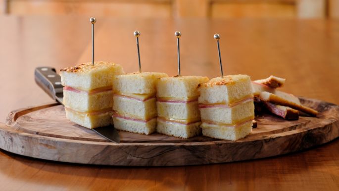 Rezeptidee, Gericht mit Käse Croque Monsieur, angerichtet auf einem Holzbrett