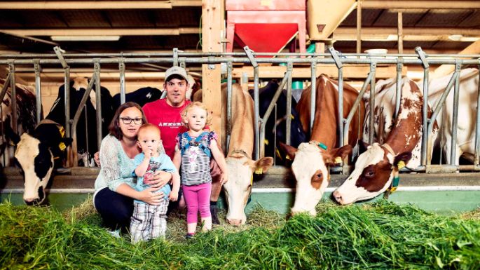 Bauernfamilie mit zwei Kindern im Kuhstall 